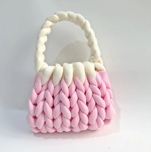 Close-up detail of pink chunky knit bag with a contrast white woven handle and soft texture