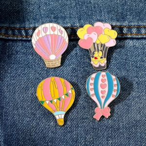 Set of four colorful hot air balloon enamel pins on blue denim fabric background
