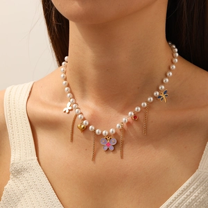 Dettaglio della collana di perle con farfalla in smalto viola e ciondoli a cuore sul modello