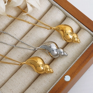 Minimalist conch shell pendant necklace in gold and silver finish displayed in a jewelry box