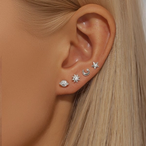 Detailed view of silver celestial stud earrings featuring planet and moon on model ear
