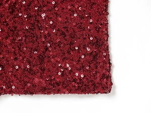 Macro shot of red sequin fabric detail showing high-gloss texture and overlap design