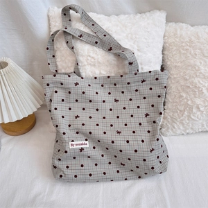 Detail of grey polka dot canvas tote bag with bow patterns and a minimalist logo tag