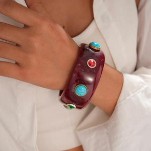 Macro detail of wine red resin bracelet with turquoise and colorful gemstone inlays