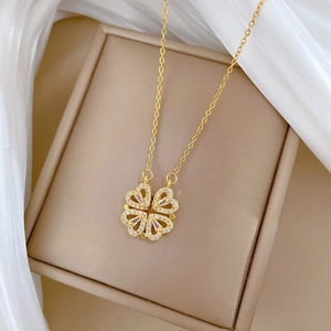 Detail of gold four-leaf clover necklace with sparkling diamonds on silk background
