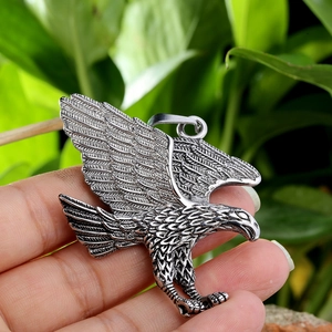 Detailed close-up of a silver stainless steel eagle pendant with intricate feather texture
