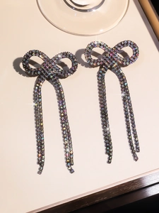 Detailed close-up of bowknot tassel earrings with shimmering rhinestones on metal base