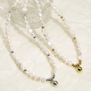 Détail de colliers en perles d'eau douce avec perles dorées et argentées sur tissu beige