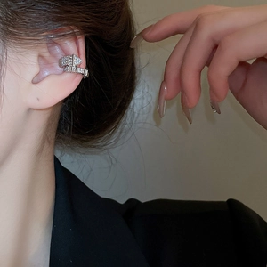 Detail view of silver zircon ear cuff with arrow design on a model wearing black suit