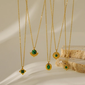 Detailed view of geometric gold-plated necklaces with emerald malachite-style pendants