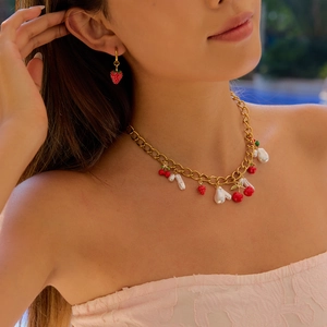 Detail of model wearing a gold necklace with cherry strawberry charms and pearl accents