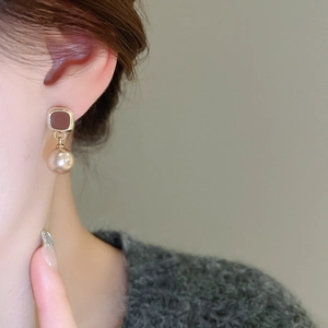 Close-up of vintage square earrings with golden borders and lustrous faux pearls