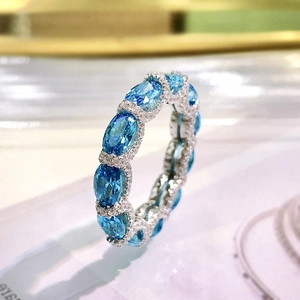 Macro shot of silver ring with oval blue gemstone and micro-pave diamond border