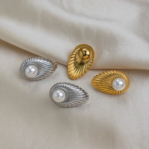 Detail view of French vintage shell striped stud earrings with pearls on beige fabric.