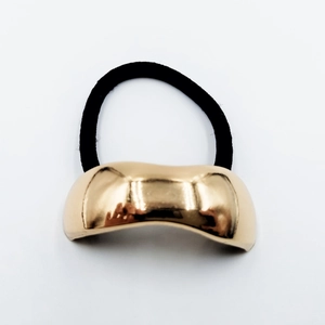 Close-up of minimalist gold metal ponytail cuff with black high-elastic hair band on white base