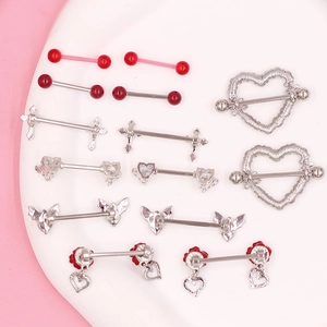 Macro shot of assorted red heart and gothic nipple rings displayed on a pink background
