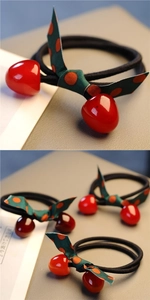 Detail of red cherry bow hair ties with elastic bands and green polka dot ribbon knots