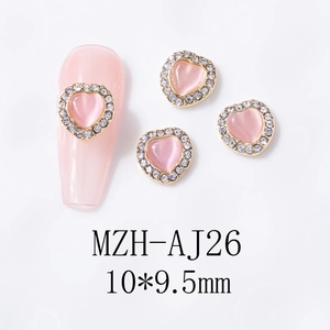 Detail of pink cat-eye heart nail charms with rhinestone border on a long nail