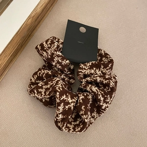 Detail view of a brown and white animal print fabric scrunchie with a small black tag