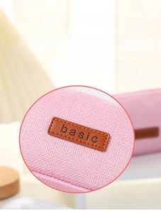 Detailed close-up of pink linen fabric texture and leather label on the pencil case