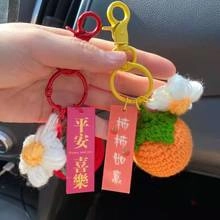 Detail of handmade crocheted flower and persimmon keychains with festive red lucky tags