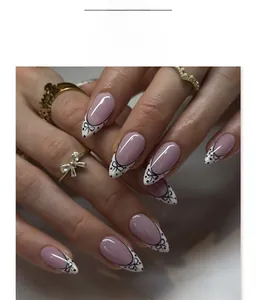 Close-up of almond press-on nails with white French tips, black bows, and polka dots