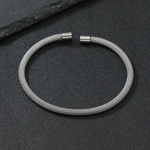 Detailed macro view of silver mesh wire steel cuff bracelet on dark stone texture