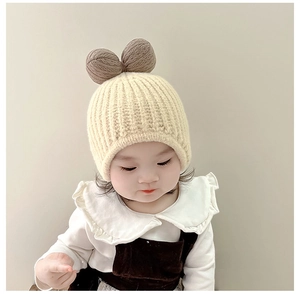 Close-up of cream knit baby hat with ribbed texture and brown bow detail