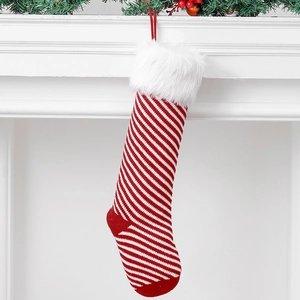 Christmas stocking with red and white stripes and plush cuff hanging from a fireplace