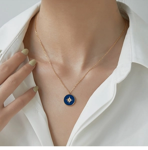 Close-up of golden nautical star necklace with blue enamel pendant on a female model