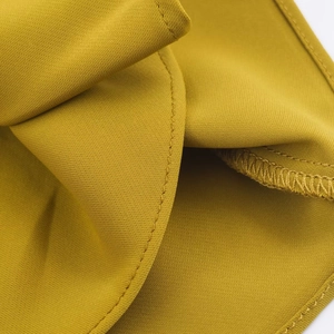 Macro view of mustard yellow halter top featuring precision stitching and woven texture