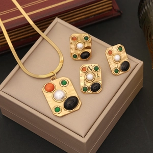 Golden jewelry set with turquoise, pearls and colorful gemstones on a beige jewelry box
