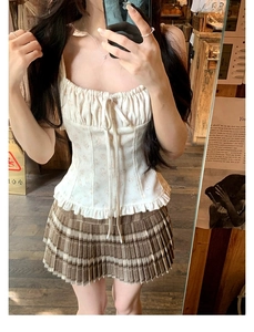 Dettaglio del top a corsetto a fiori con coulisse e minigonna a pieghe scozzese marrone