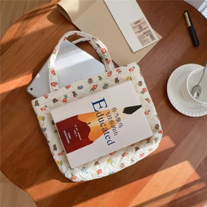 Detailed top view of a white quilted bear tote bag on a wooden desk with a sunny vibe