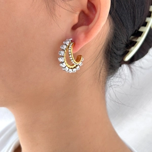 Detail view of 18K gold plated double C-shaped earrings with zircon inlay worn by model