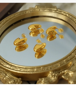 Detailed macro view of 18K gold plated bean stud earrings on a vintage mirror reflection