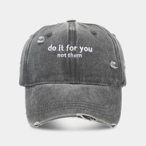 Detail of vintage washed grey baseball cap with embroidery and distressed hole effects