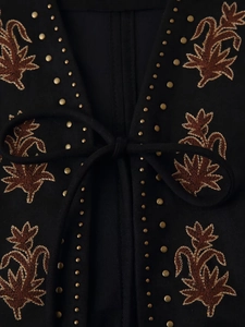 Détail du gilet ethnique noir avec broderies marrons, clous dorés et fermeture à lacets
