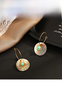 Detailed macro view of natural shell earrings with turquoise beads and sunburst accents