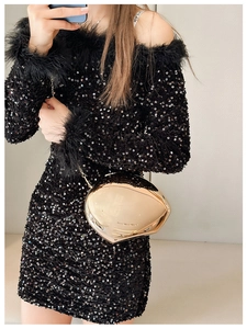 Close-up of a gold oval metal clutch bag with a fine chain strap and mirror finish