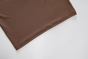 Détail de la couture et texture du tissu tricoté marron foncé sur l'ourlet du haut
