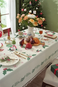 Detail of Christmas tablecloth with reindeer print, tassels, and holiday decor setup