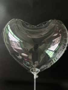 Detail of heart-shaped transparent PVC balloon with LED light string on a white pole