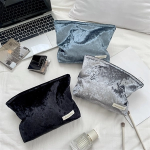 Three colors of velvet makeup bags shown in a lifestyle scene with luxury cosmetics