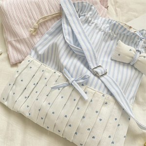 Detailed close-up of blue striped canvas bag with bow accent and heart print pleats
