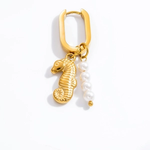 Detail of U-shaped gold earring featuring a textured seahorse and white pearl pendant
