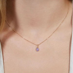 Elegant gold necklace with purple oval zircon pendant worn on a model's neck