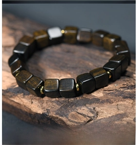Macro shot of cubic dark wood prayer beads with golden spacers on natural wood