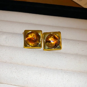 Close-up of geometric square resin earrings with gold metal frame and amber center