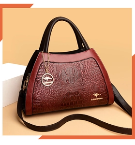 Detailed close-up of wine red crocodile pattern leather with gold kangaroo logo and charms
